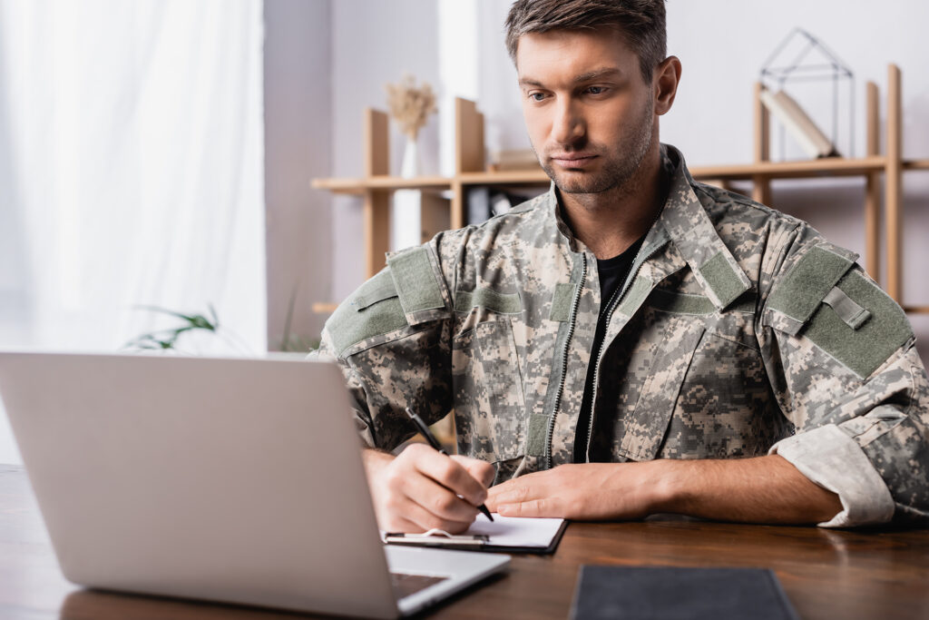 A military student using a laptop to attend online college classes from home