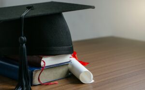 Close up mortar board with degree paper on wood table. graduation concept.