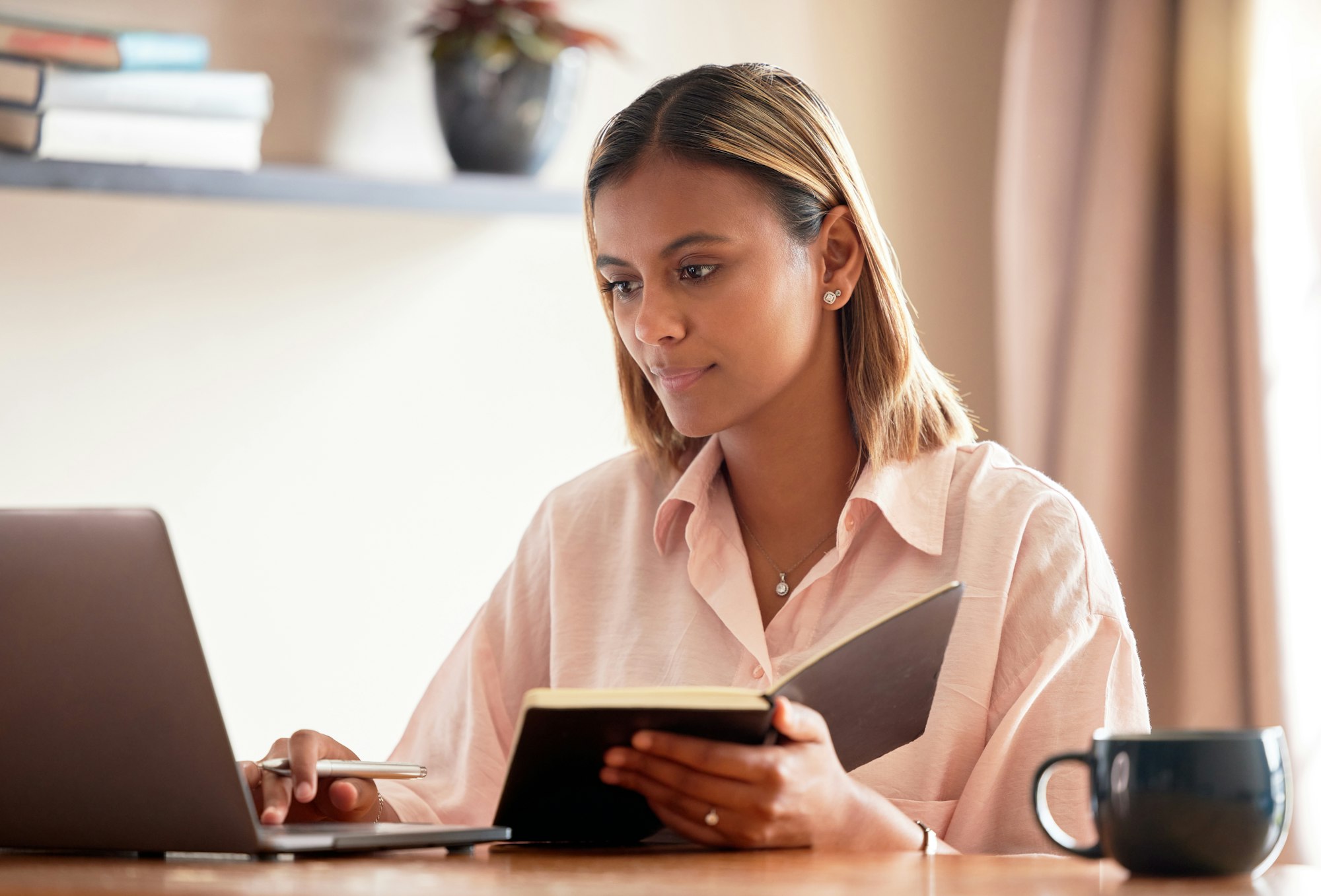 Laptop, student and woman with book for online learning, studying or research in home. Scholarship,