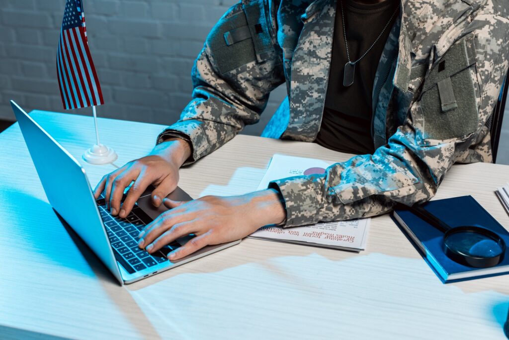 cropped view of military man typing on laptop in office