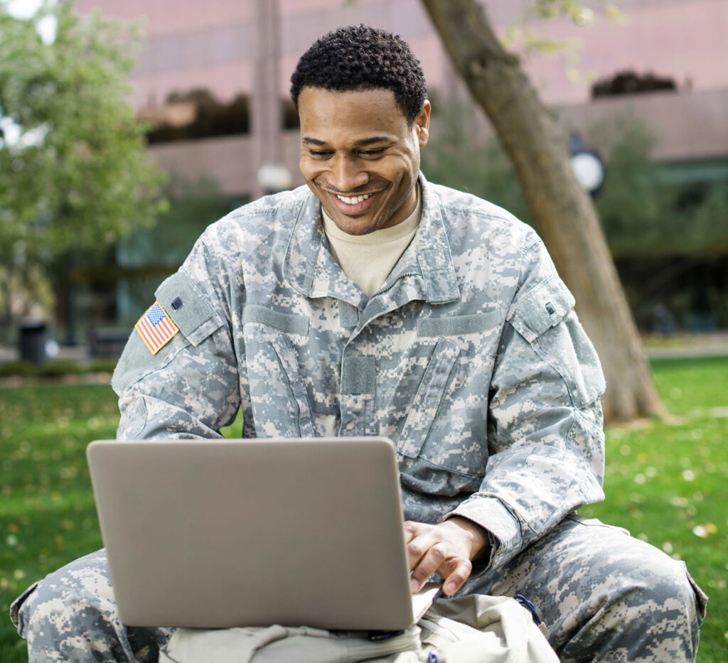 Active-duty military member researching online college options with laptop
